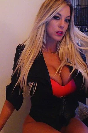 Smiling blonde chick Xo Gisele is playing with her enormous boobs before the camera