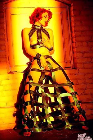 Redhead Justine Joli in amazing dress made of leather belts poses in the empty room