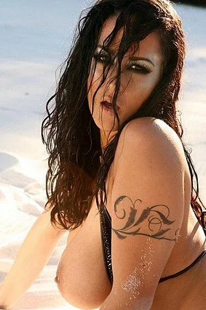 Curvy brunette Carmella Bing in black bikini shows her juggs and snatch in sand